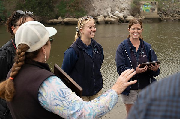 Two of the four people in the photo have their faces in full view as these two are smiling. One is holding a thin object in their hands.