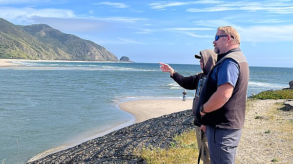two people observe the ocean along the coastline