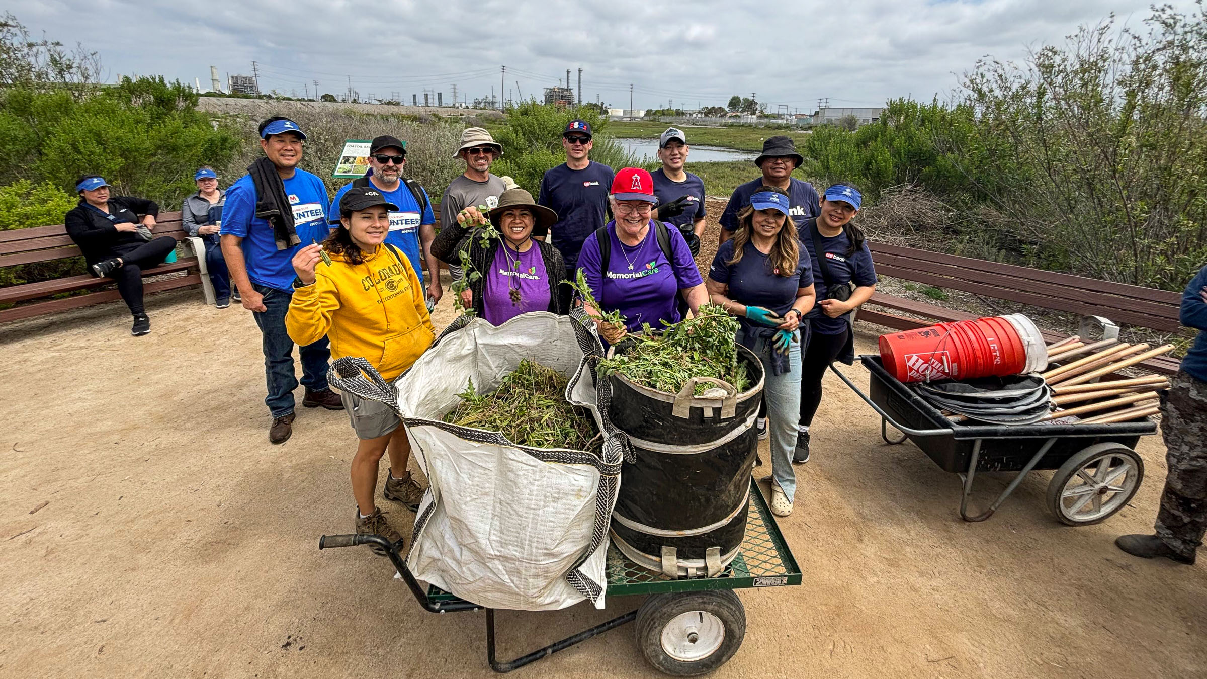 Group of people posing with grass filled wheelbarrow
