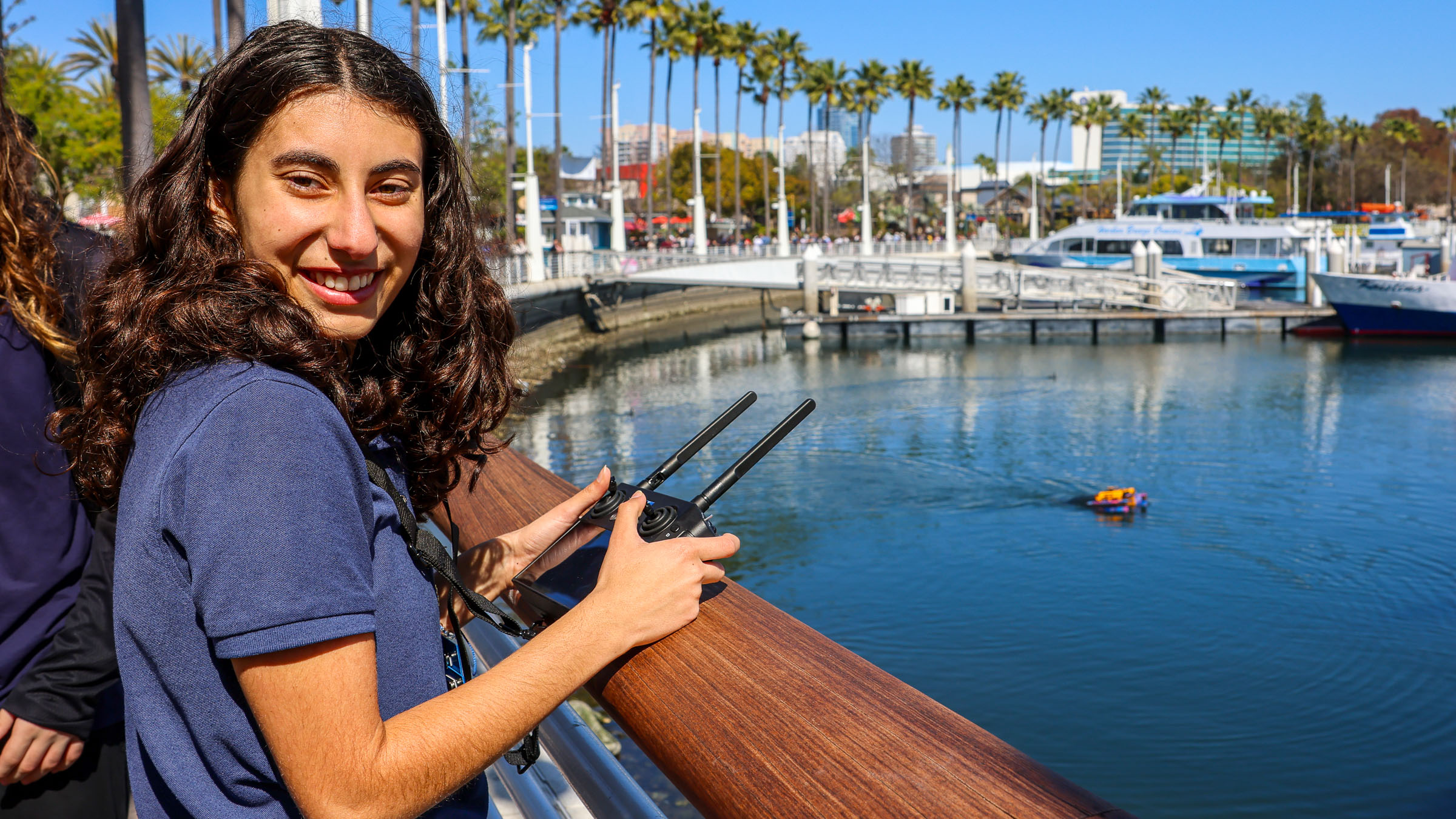 Woman remote controlling water robot on pier