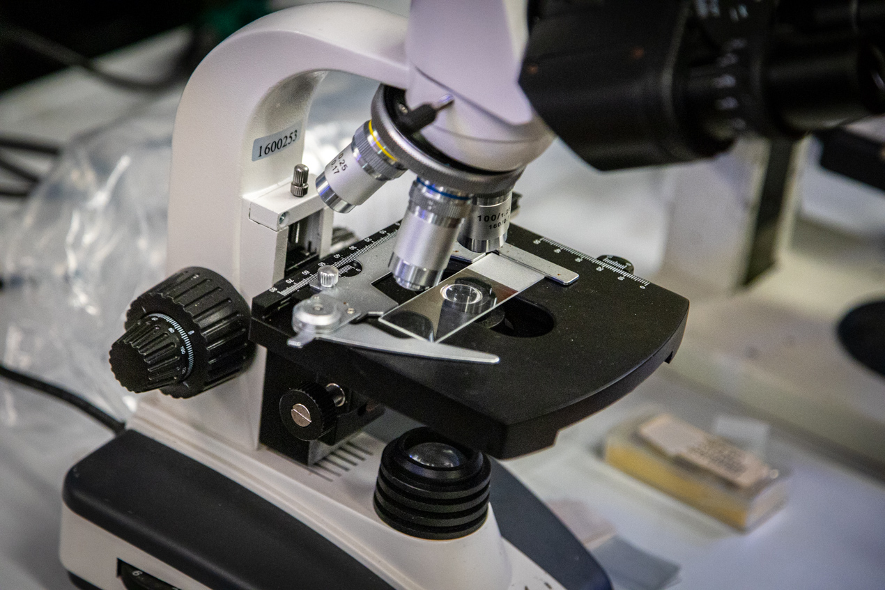 close up of a black and white microscope with a slide on the stage