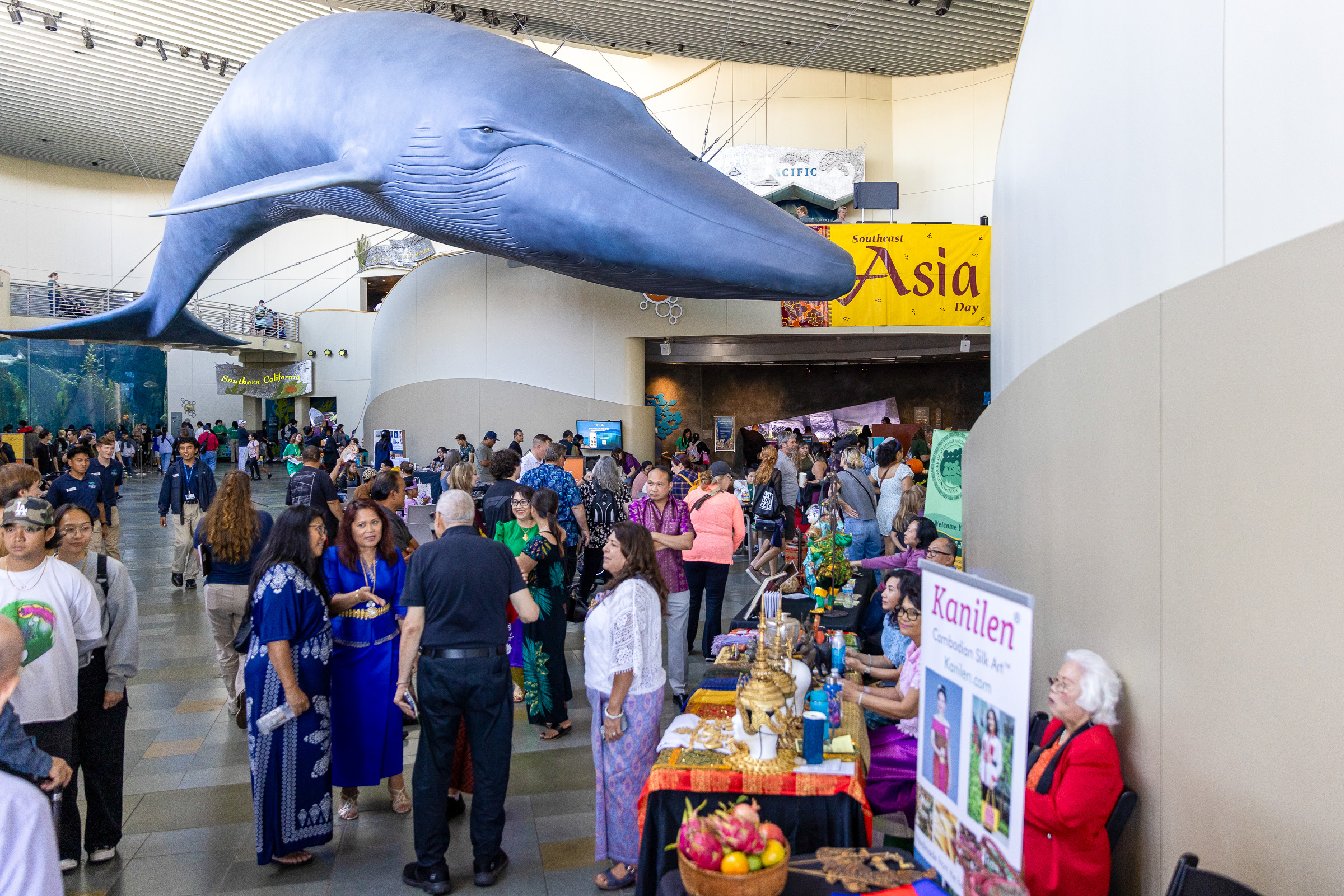 Great Hall of Aquarium with people talking in groups below the blue whale sculpture
