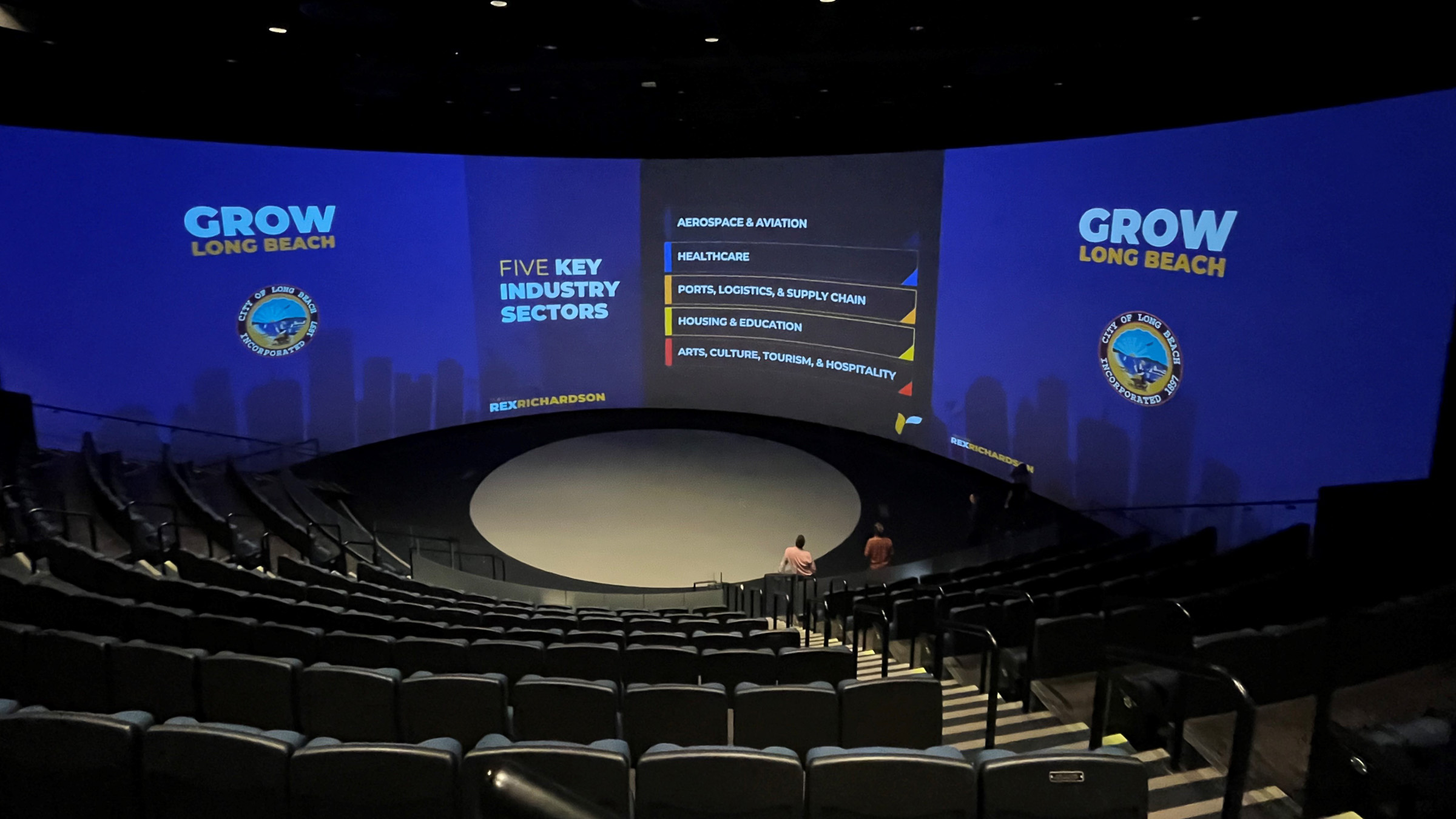View of theater with empty chairs and Grow Long Beach infographics on screen