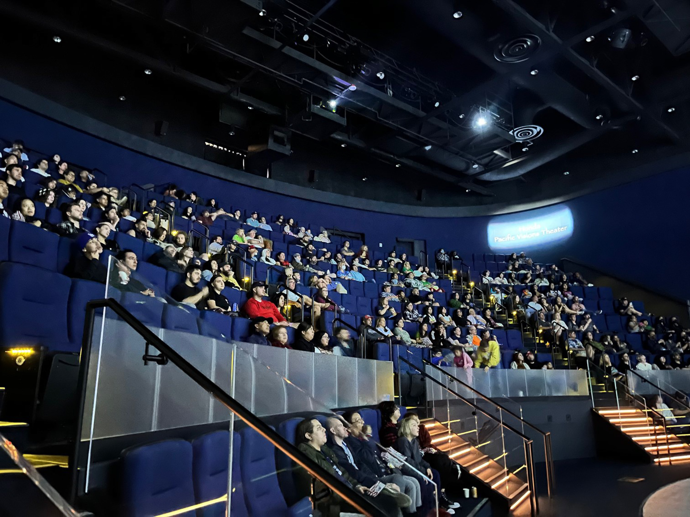 Interior of theater with many people in seats facing the screen