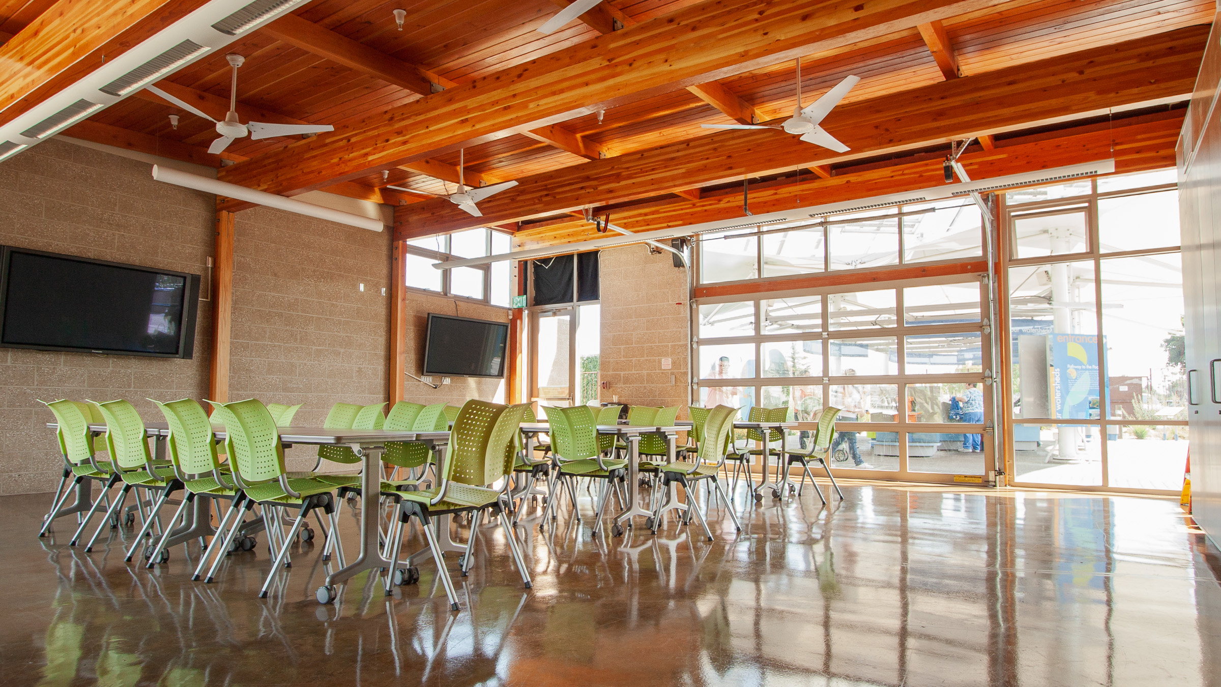 Interior of classroom showing wood ceiling and green chairs and tables